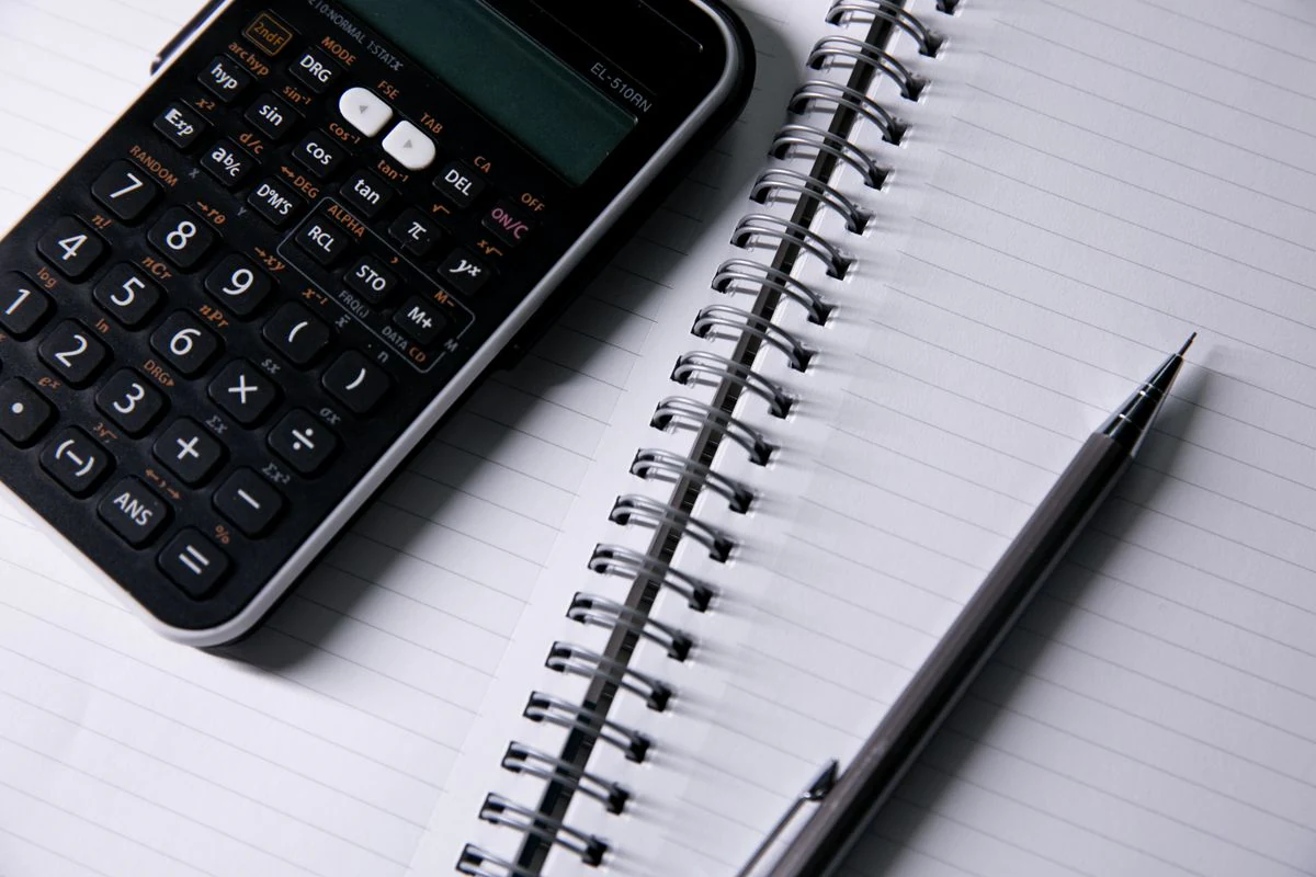 A notebook, a calculator and a pen on a desk